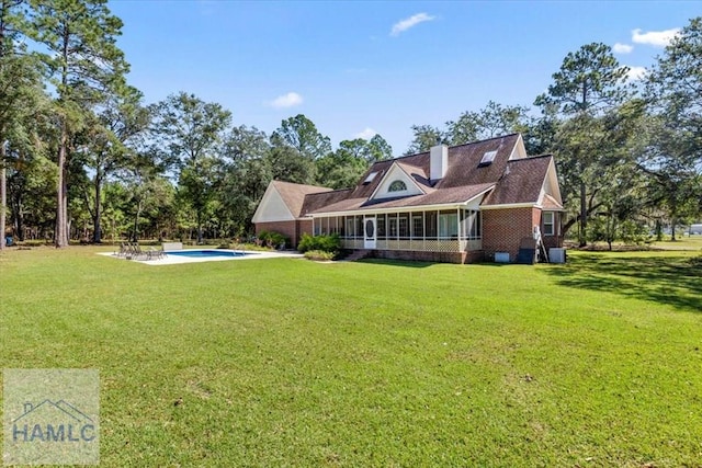 rear view of property featuring a yard and a sunroom