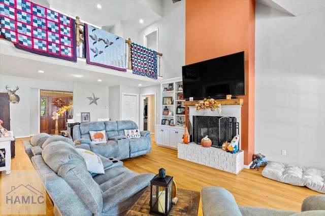 living room featuring a fireplace, wood-type flooring, built in features, and a high ceiling