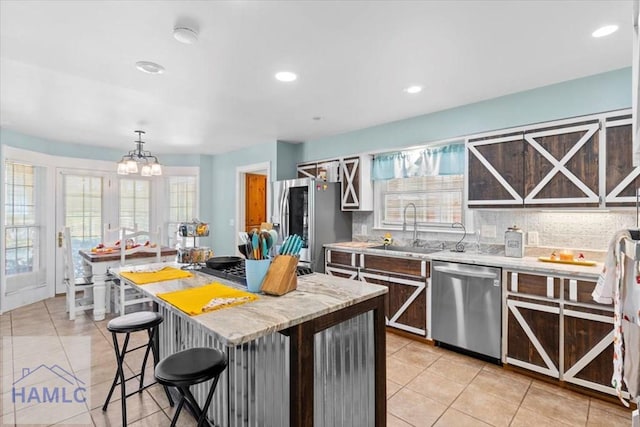 kitchen with backsplash, stainless steel appliances, sink, pendant lighting, and a kitchen island