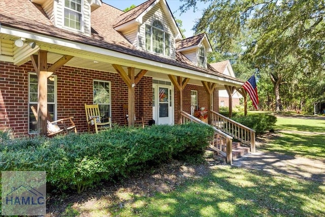 view of exterior entry with a lawn and covered porch