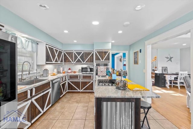 kitchen featuring sink, stainless steel appliances, backsplash, a kitchen bar, and light wood-type flooring