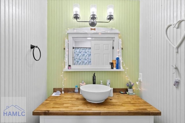 bathroom featuring wooden walls and vanity