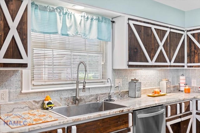 kitchen featuring stainless steel dishwasher, backsplash, light stone counters, and sink