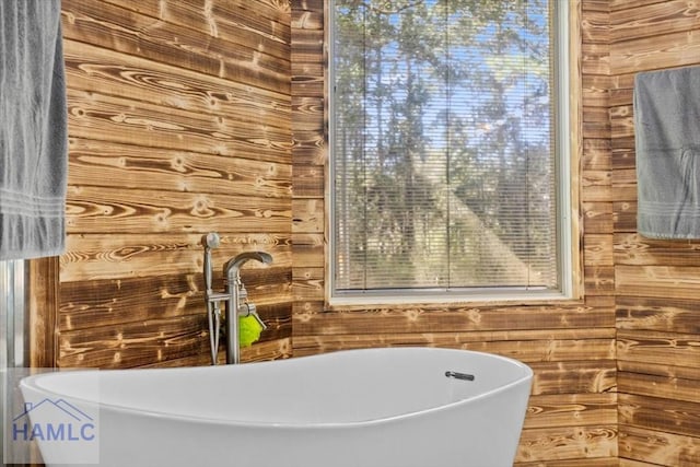 bathroom with sink, a tub to relax in, and wooden walls