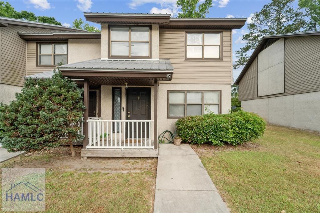 601 Tupelo Trl Unit 39I, Hinesville, GA 31313 - view of front of house with metal roof, a front yard, and stucco siding