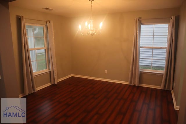 unfurnished room featuring dark hardwood / wood-style floors and a notable chandelier