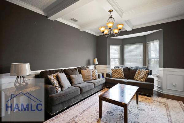 246 Cumberland Dr NE, Ludowici, GA 31316 - living area with a chandelier, a wainscoted wall, ornamental molding, beamed ceiling, and wood finished floors