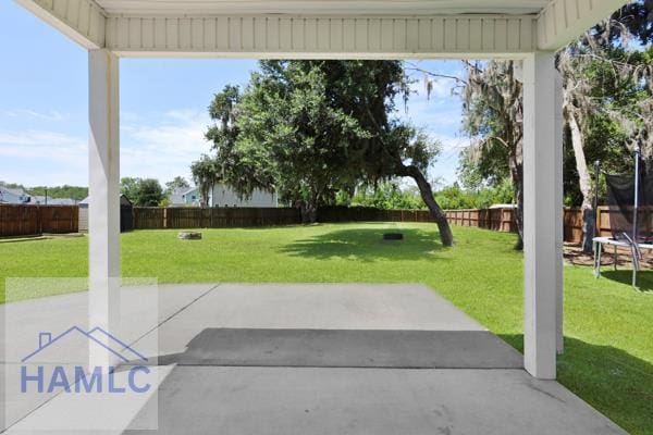246 Cumberland Dr NE, Ludowici, GA 31316 - fenced backyard with a trampoline and a patio area