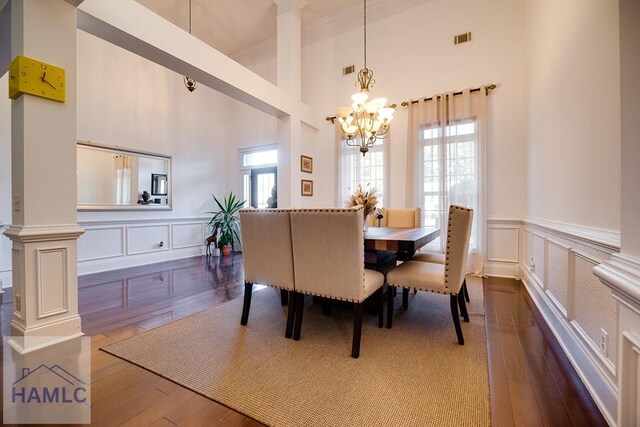 86 Brigham Dr, Richmond Hill, GA 31324 - dining room featuring a chandelier, a decorative wall, wood finished floors, ornamental molding, and a high ceiling