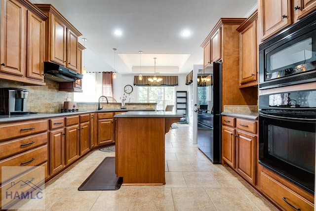 86 Brigham Dr, Richmond Hill, GA 31324 - kitchen featuring black appliances, under cabinet range hood, a chandelier, a raised ceiling, and decorative backsplash