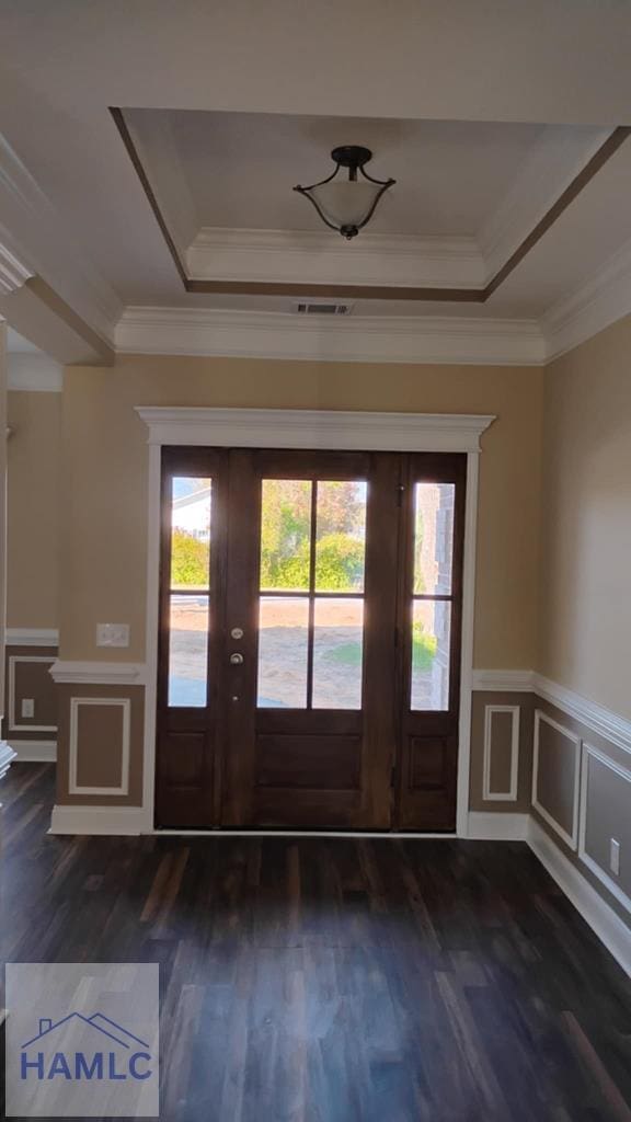 entryway with visible vents, a tray ceiling, dark wood-style floors, and ornamental molding