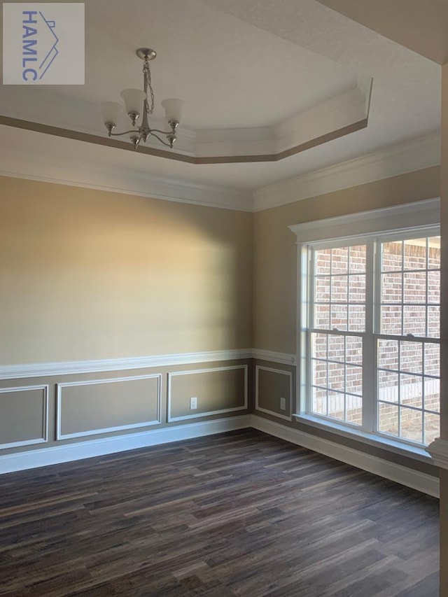 unfurnished room with dark wood-style floors, a notable chandelier, ornamental molding, and a tray ceiling