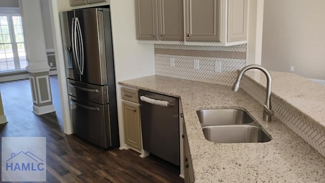 kitchen with dark wood finished floors, a sink, light stone countertops, tasteful backsplash, and appliances with stainless steel finishes