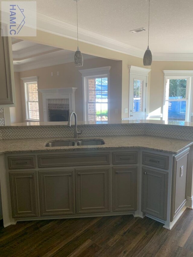 kitchen featuring a sink, a fireplace, dark wood-style flooring, light stone countertops, and visible vents