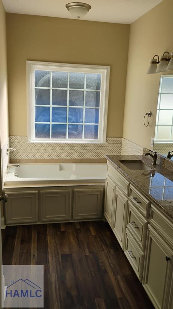 bathroom featuring wood finished floors, a garden tub, and vanity