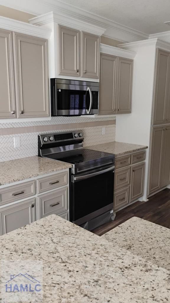 kitchen with backsplash, ornamental molding, appliances with stainless steel finishes, and dark wood-style flooring