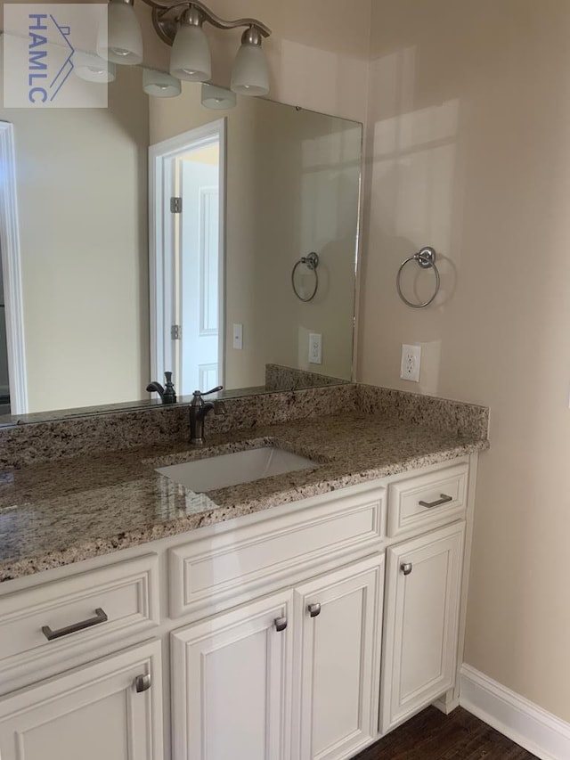 bathroom with baseboards, wood finished floors, and vanity