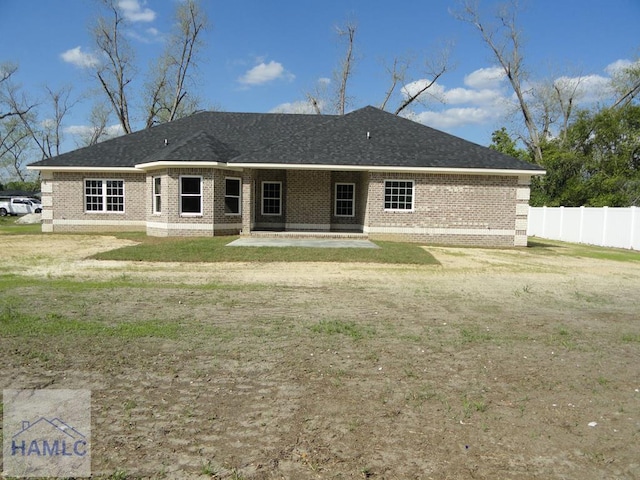 rear view of house featuring brick siding, a yard, a patio, and fence