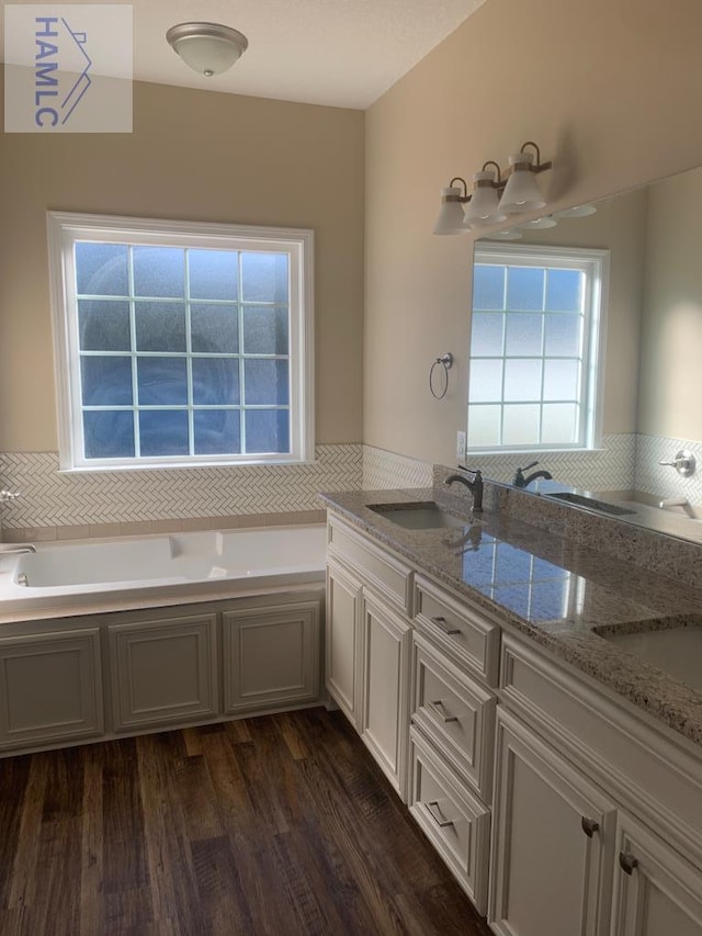 bathroom featuring a bath, wood finished floors, and a sink
