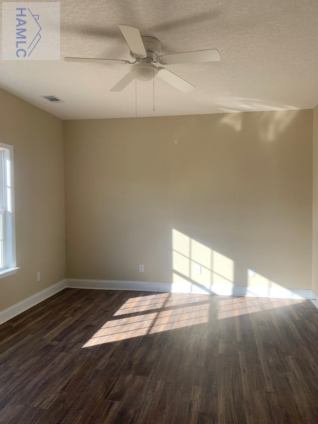 unfurnished room with visible vents, baseboards, dark wood-style floors, and a textured ceiling
