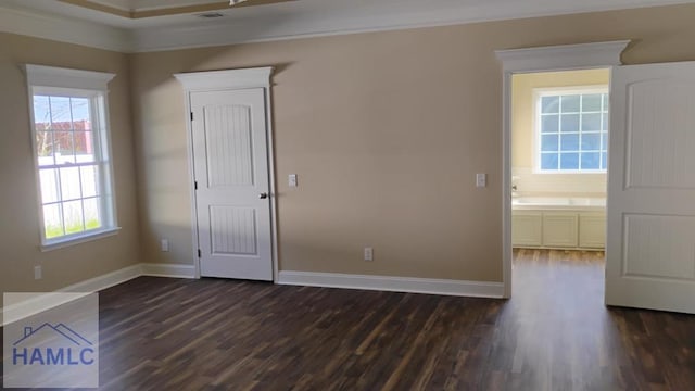 spare room featuring dark wood-type flooring, a healthy amount of sunlight, baseboards, and ornamental molding