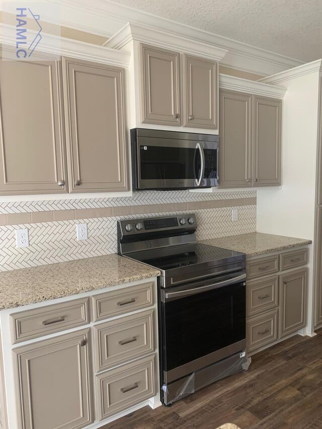 kitchen with decorative backsplash, ornamental molding, cream cabinetry, and stainless steel appliances