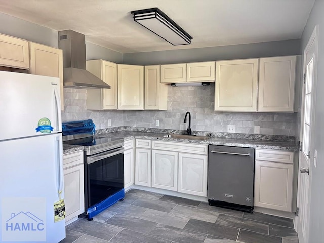 kitchen featuring a sink, stainless steel appliances, cream cabinets, wall chimney range hood, and tasteful backsplash