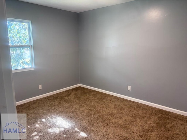 empty room featuring baseboards and dark colored carpet