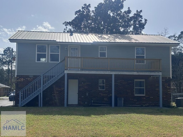 back of property with stairs, a lawn, brick siding, and metal roof