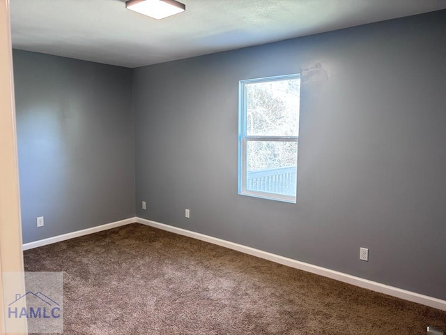 empty room with baseboards and dark carpet