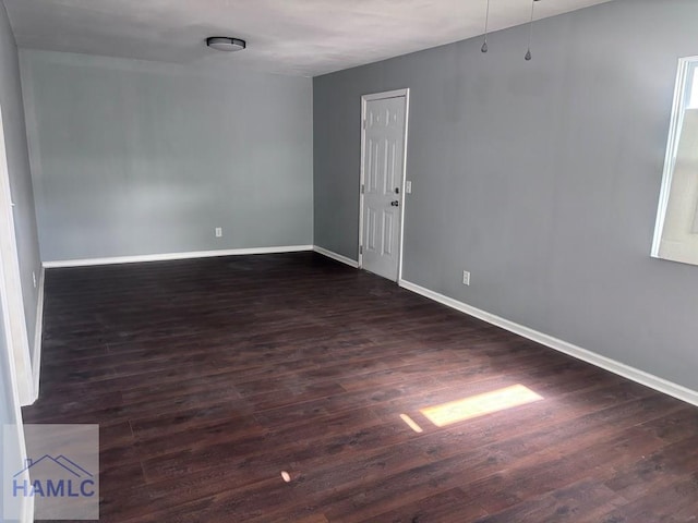 spare room featuring baseboards and dark wood finished floors