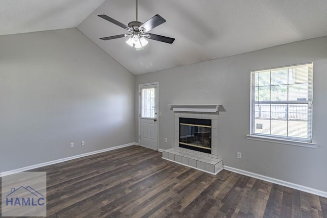 unfurnished living room with baseboards, a tiled fireplace, vaulted ceiling, wood finished floors, and a ceiling fan