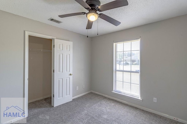 unfurnished bedroom featuring visible vents, a textured ceiling, a closet, and carpet flooring