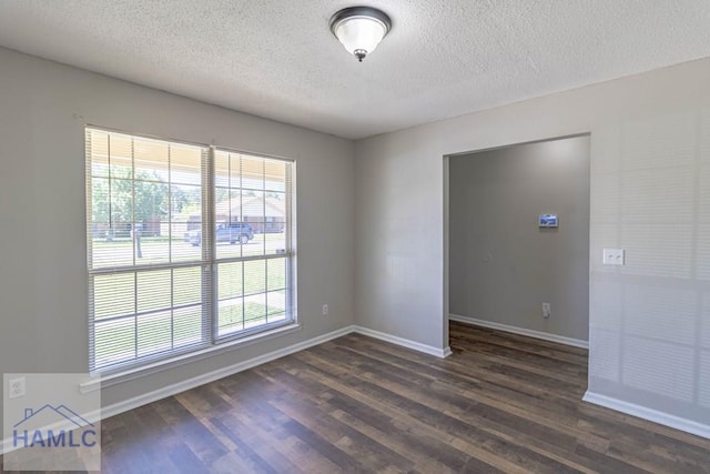 spare room with baseboards, a textured ceiling, and dark wood-style floors