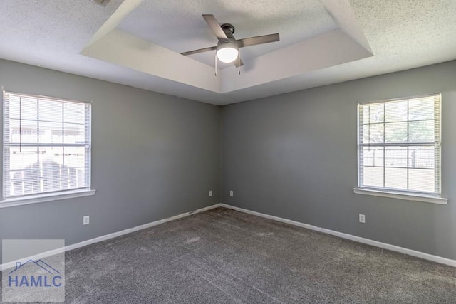 carpeted empty room featuring a raised ceiling, a ceiling fan, baseboards, and a textured ceiling