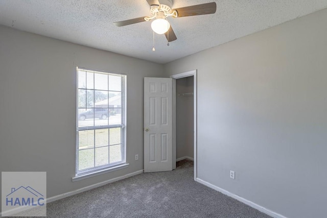 carpeted spare room with baseboards, plenty of natural light, and a textured ceiling