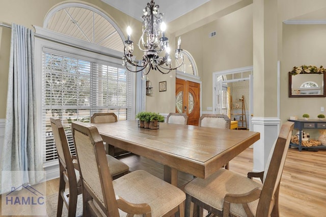 dining room with light hardwood / wood-style floors, a chandelier, and a towering ceiling