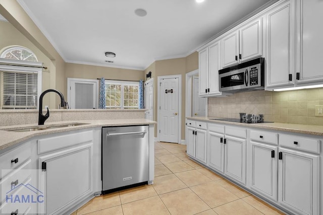 kitchen featuring appliances with stainless steel finishes, white cabinetry, sink, backsplash, and light tile patterned floors