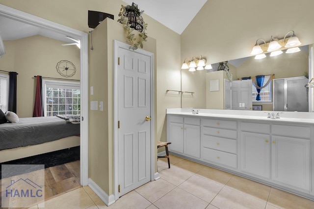 bathroom featuring vanity, vaulted ceiling, walk in shower, and tile patterned floors