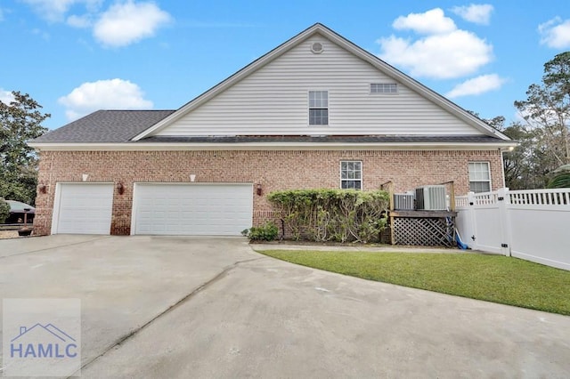 view of side of home with a garage, cooling unit, and a lawn