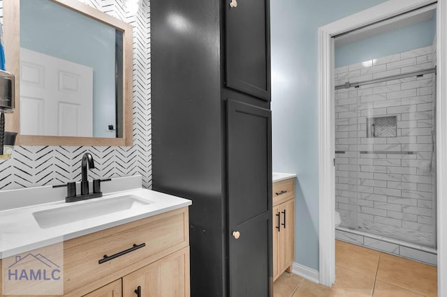 bathroom with toilet, tile patterned flooring, tiled shower, vanity, and backsplash