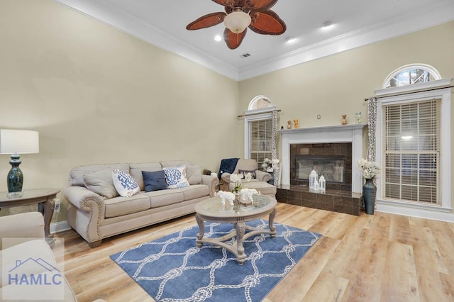 living room featuring hardwood / wood-style flooring, crown molding, ceiling fan, and a fireplace