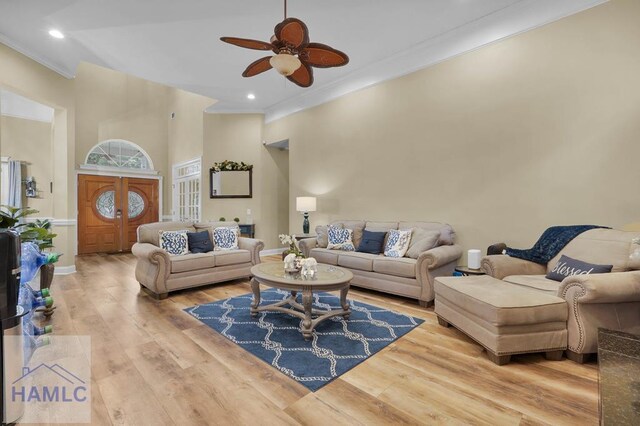 living room with ceiling fan, crown molding, and light wood-type flooring