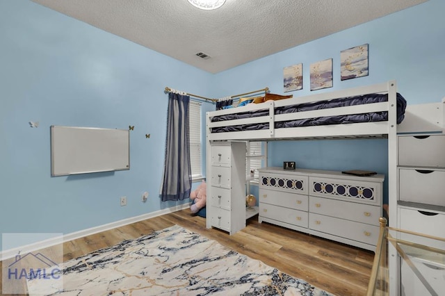 bedroom with a textured ceiling and hardwood / wood-style floors