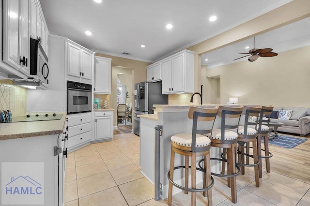 kitchen featuring decorative backsplash, white cabinets, ornamental molding, a breakfast bar, and stainless steel appliances