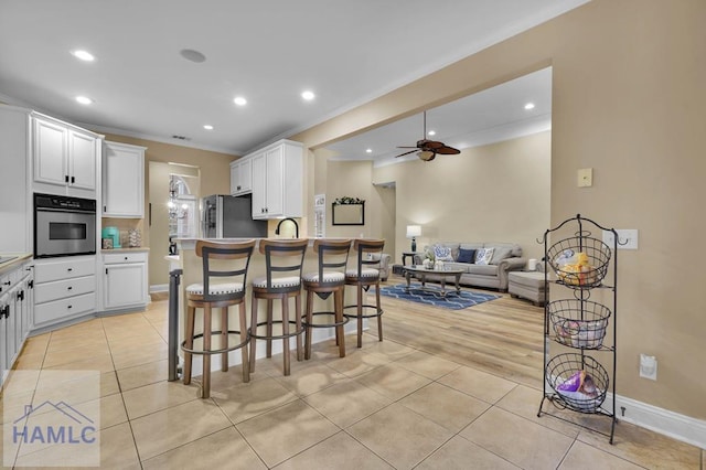 kitchen with stainless steel appliances, white cabinetry, light tile patterned floors, and a breakfast bar