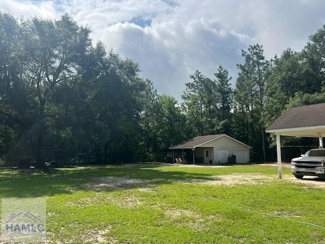 189 Sooner Dr, Jesup, GA 31545 - view of grassy yard featuring a detached garage, an outdoor structure, and a forest view