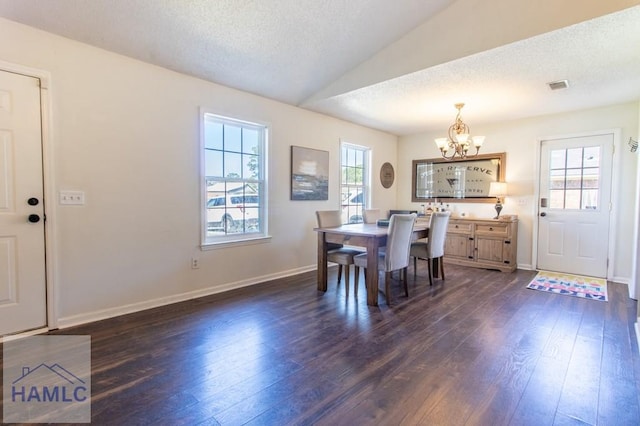 dining space featuring visible vents, dark wood-type flooring, an inviting chandelier, vaulted ceiling, and a textured ceiling