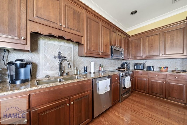 745 Chickasaw Trl, Sparta, GA 31087 - kitchen featuring appliances with stainless steel finishes, a sink, light stone countertops, light wood-style floors, and crown molding