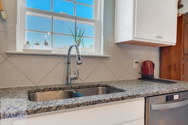 kitchen with a healthy amount of sunlight, dishwasher, white cabinets, a sink, and backsplash